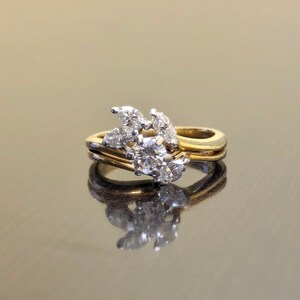 May include: A gold and white diamond ring with a cluster of pear-shaped and round diamonds set in a leaf-like design.