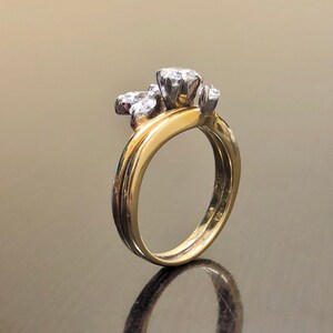 May include: A gold and silver wedding band set with a cluster of small diamonds. The band is set with a single larger diamond in the center.