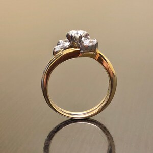 May include: A gold band ring with a cluster of three diamonds set in a flower shape.