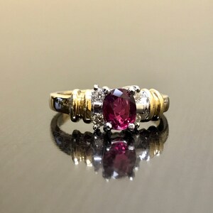 May include: A gold and silver ring with a large oval-shaped purple gemstone surrounded by smaller diamonds.