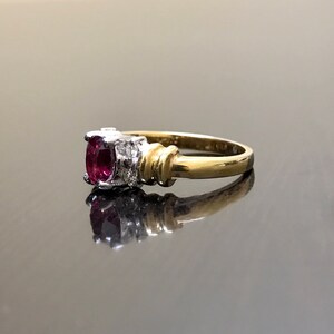 May include: A gold ring with a red oval gemstone and smaller white gemstones on the band.