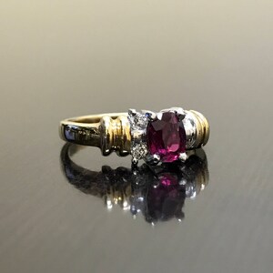 May include: A gold and silver ring with a large oval-shaped purple gemstone surrounded by smaller diamonds.