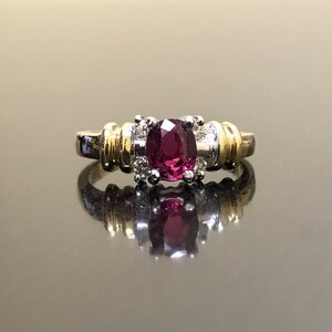 May include: A gold and silver ring with a large oval-shaped purple gemstone surrounded by smaller diamonds.