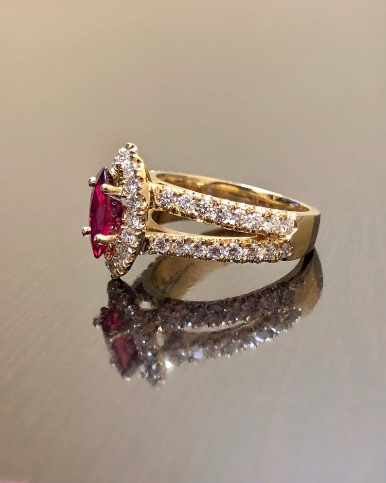 May include: A gold ring with a marquise-shaped ruby surrounded by a halo of smaller diamonds. The ring has a split shank with a row of diamonds on each side.