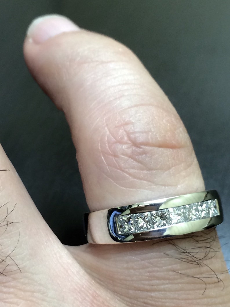 K&ouml;nnte beinhalten: Ein silberner Ring mit einer Reihe quadratischer Diamanten, die in einer Kanalfassung gefasst sind.