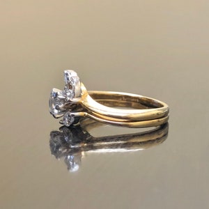 May include: A gold wedding band set with a diamond cluster ring. The cluster ring features a central diamond surrounded by smaller diamonds.