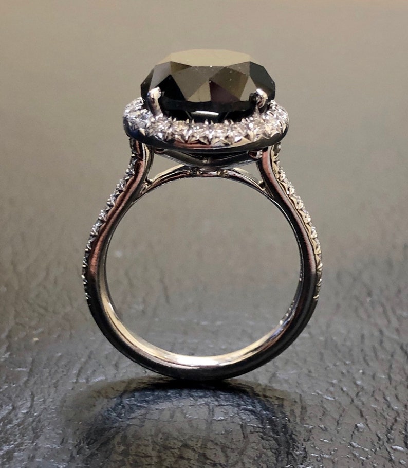 May include: A black diamond engagement ring with a halo of smaller diamonds set in a white gold band.