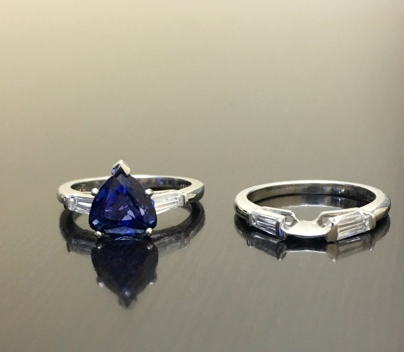 May include: A pair of engagement rings with a pear-shaped sapphire center stone and baguette-cut diamonds on the band. The rings are set in white gold.