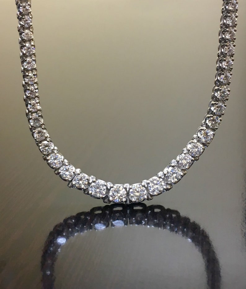 May include: A diamond tennis necklace with a silver chain and round brilliant cut diamonds.