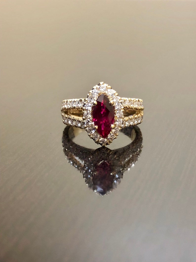 May include: A gold ring with a marquise-shaped ruby surrounded by a halo of small diamonds. The ring has a delicate band with additional diamonds.