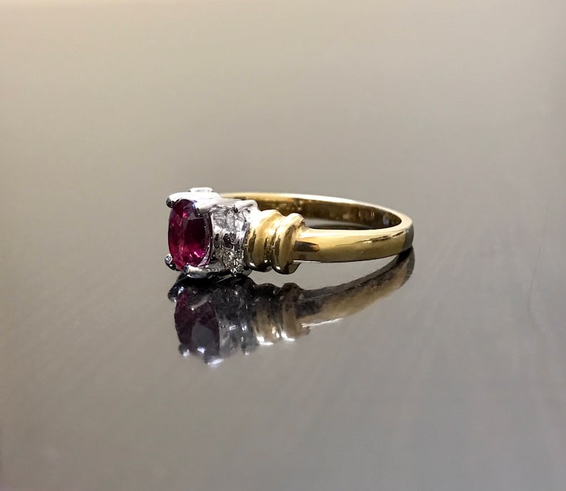 May include: A gold ring with a red oval gemstone and smaller white gemstones on the band.