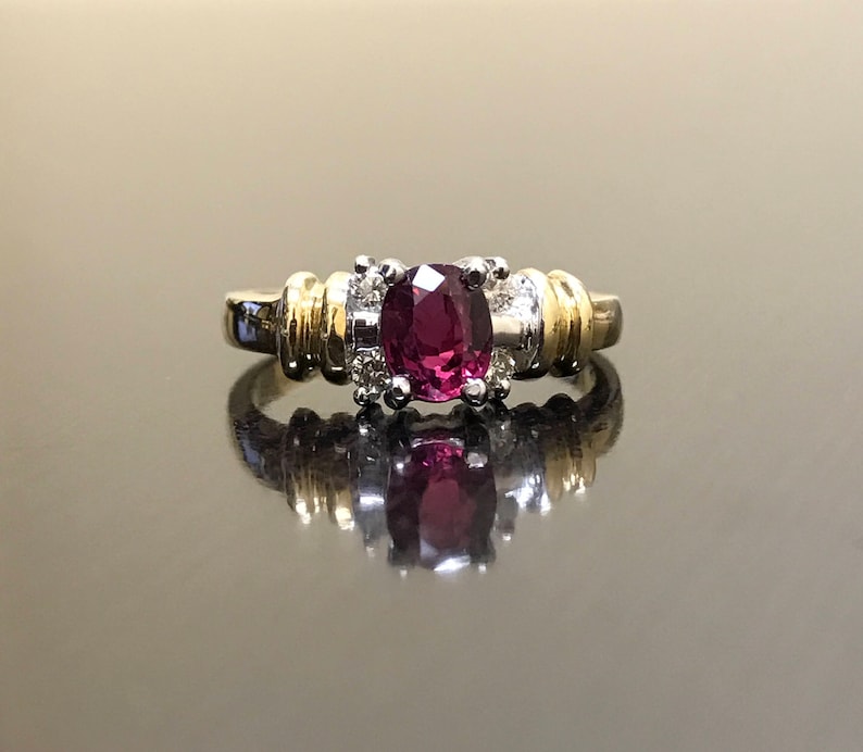 May include: A gold and silver ring with a large oval-shaped purple gemstone surrounded by smaller diamonds.
