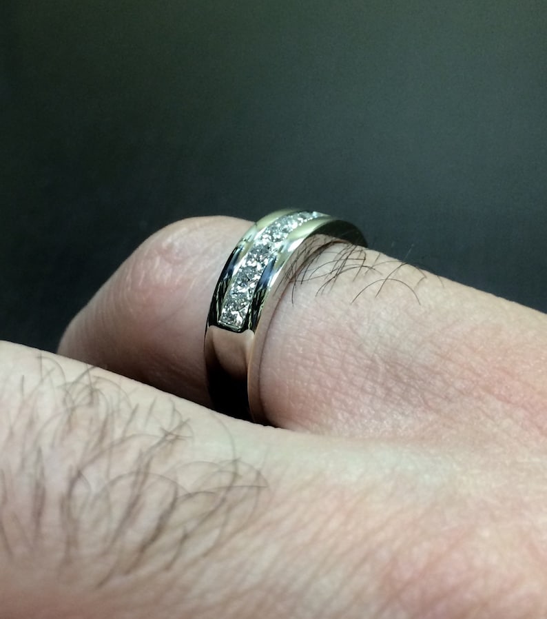 K&ouml;nnte beinhalten: Ein silberner Ring mit einer Reihe kleiner, klarer Diamanten, die in einer Kanalfassung gefasst sind.