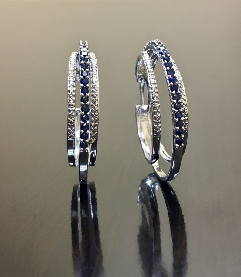 May include: A pair of silver hoop earrings with a double row of blue sapphires and a single row of white diamonds.