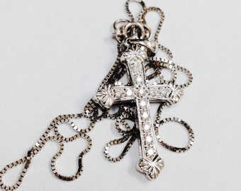 May include: A silver chain necklace with a silver cross pendant encrusted with small clear stones.