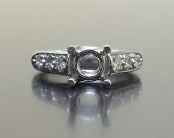 May include: A silver ring with a round setting for a center stone and small round stones set in the band.