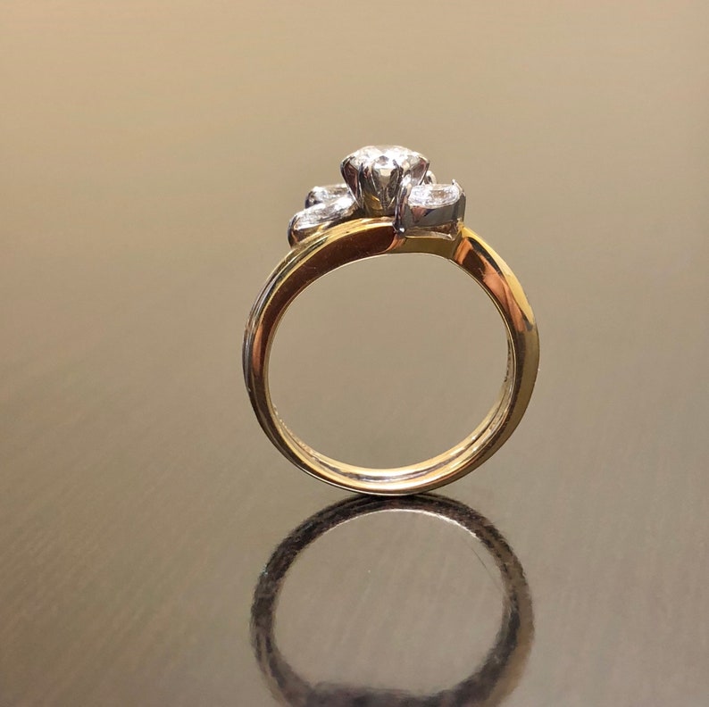 May include: A gold band ring with a cluster of three diamonds set in a flower shape.