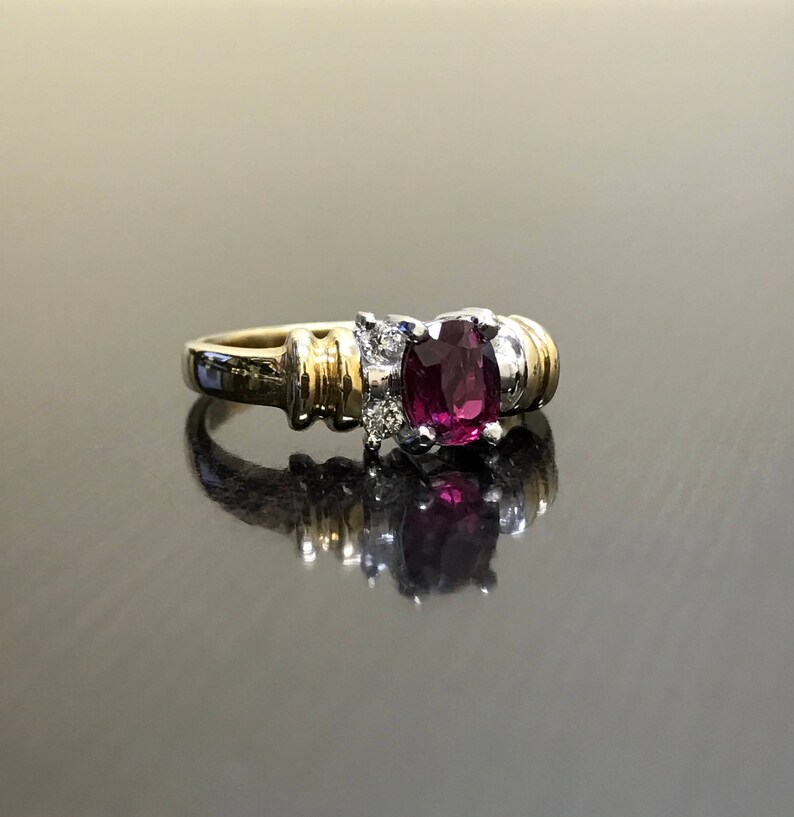 May include: A gold and silver ring with a large oval-shaped purple gemstone surrounded by smaller diamonds.