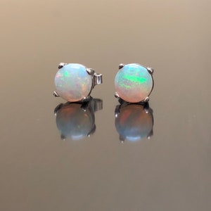 May include: A pair of silver stud earrings with round white opal gemstones.