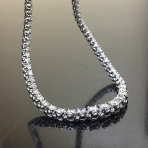 May include: A silver chain necklace with small, round, clear stones set in a continuous line.