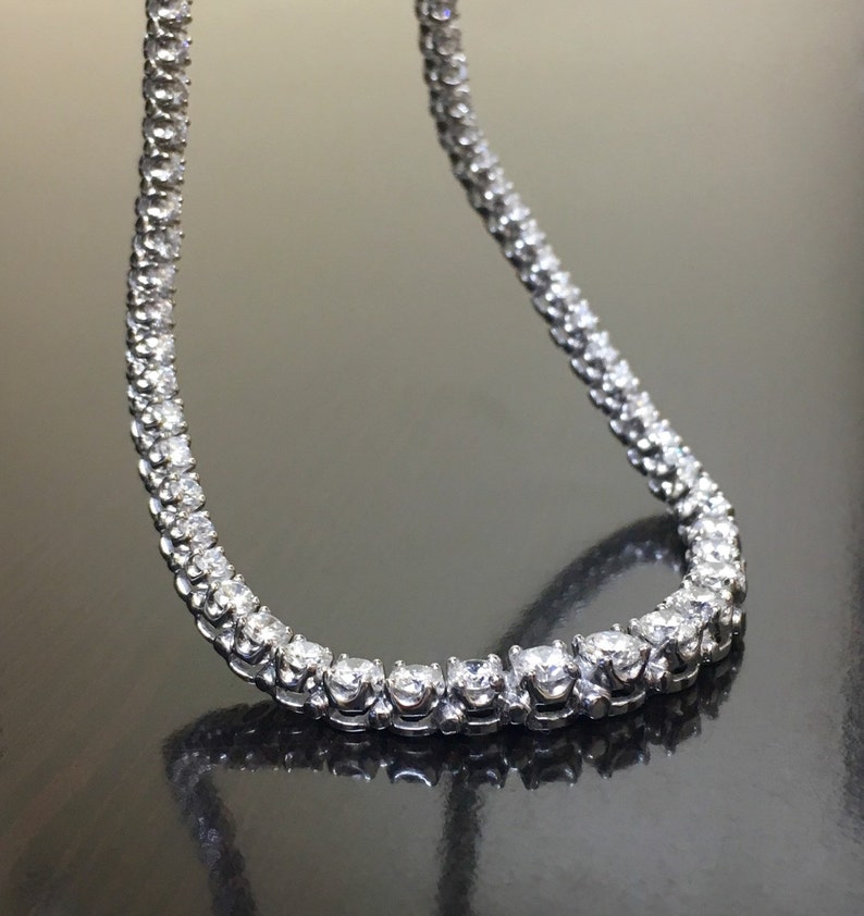 May include: A silver chain necklace with small, round, clear stones set in a continuous line.