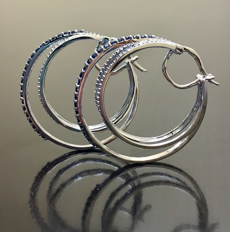 May include: Silver hoop earrings with multiple rows of blue gemstones.