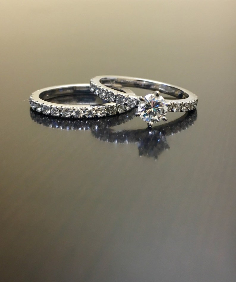 May include: A set of two silver wedding bands with a single round diamond on the top band. Both bands are set with small diamonds.