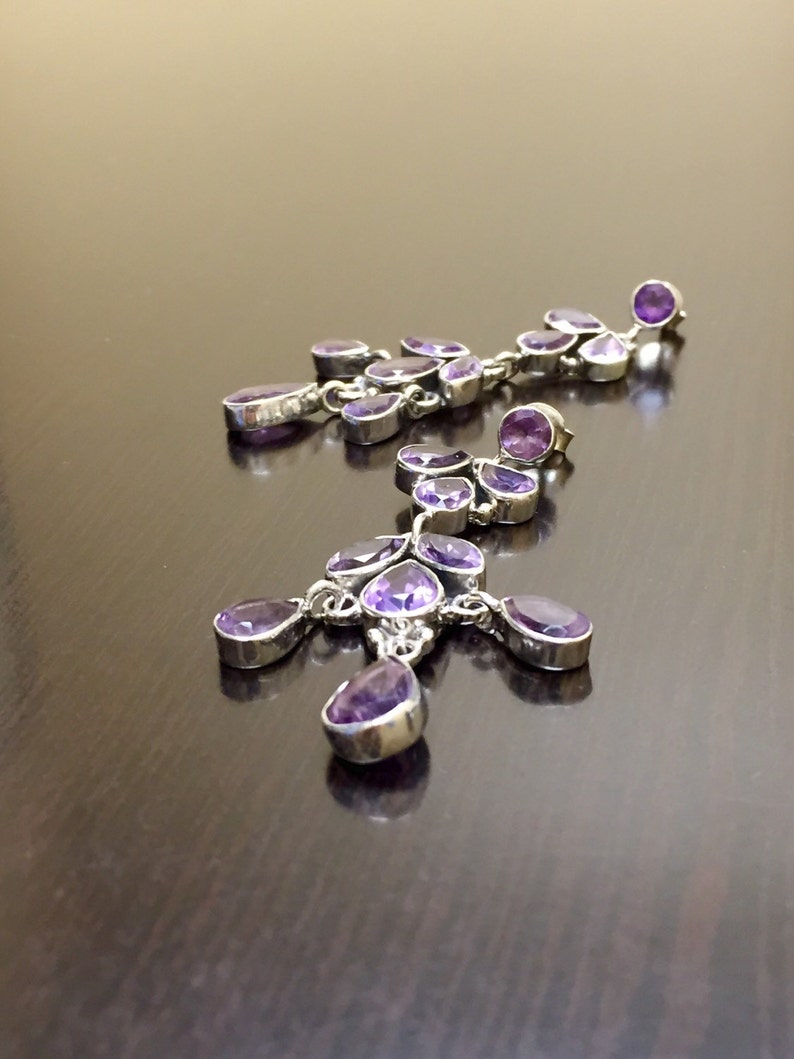 May include: A pair of dangle earrings with multiple purple amethyst stones and silver settings.