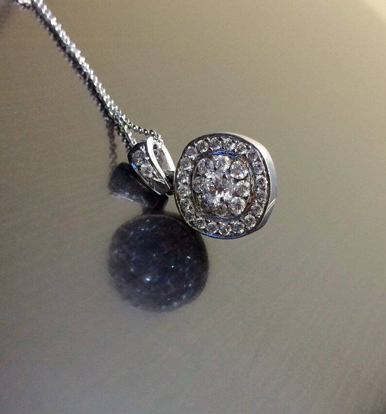 May include: A silver necklace with a round pendant featuring a cluster of small diamonds.