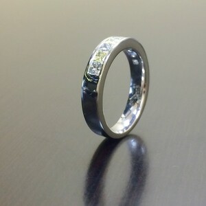 May include: A silver band with a row of clear square-shaped stones set in the band.