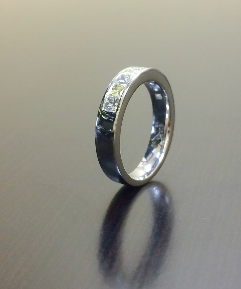May include: A silver band with a row of clear square-shaped stones set in the band.