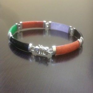 May include: A multi-colored jade bracelet with a silver clasp. The bracelet is made of green, orange, black, and purple jade.