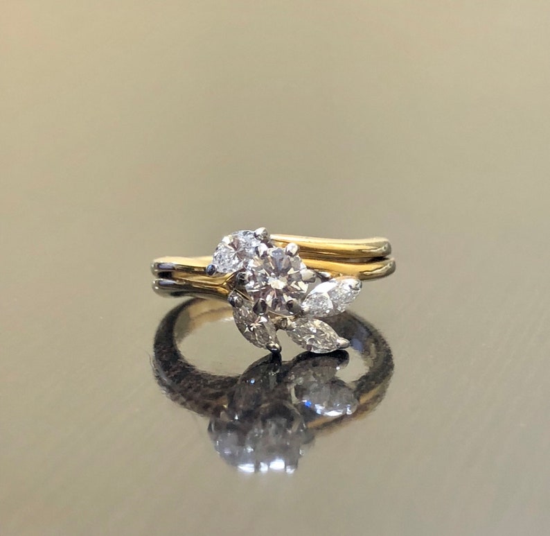 May include: A gold and silver engagement ring with a round center diamond and smaller diamonds set in a leaf design.