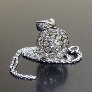 May include: A silver chain necklace with a pendant featuring a round cluster of sparkling diamonds.
