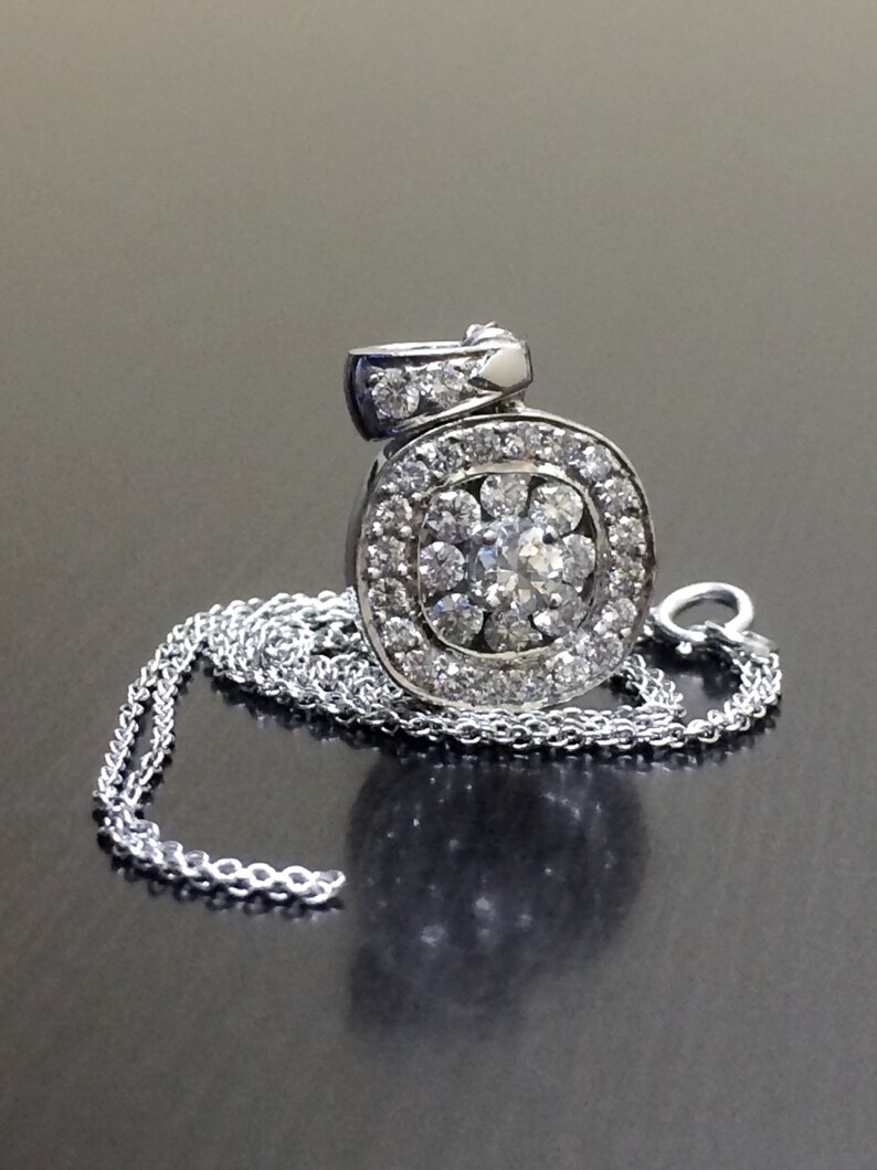 May include: A silver chain necklace with a pendant featuring a round cluster of sparkling diamonds.
