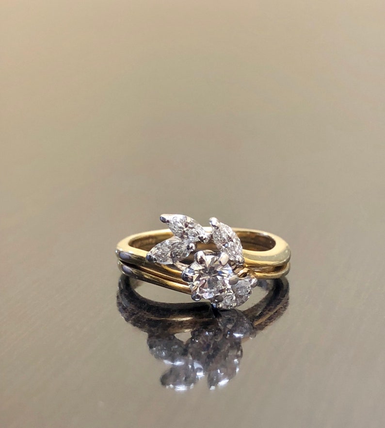 May include: A gold and white diamond engagement ring with a round center stone and a leaf design. The ring is set on a black background.