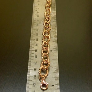 Puede incluir: Un brazalete de cadena dorado con cierre de langosta. El brazalete mide aproximadamente 20 cm de largo.