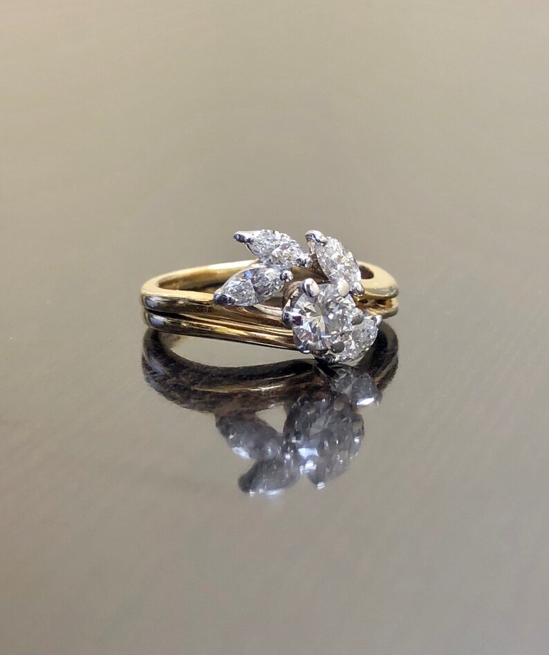 May include: A gold and white diamond engagement ring with a floral design. The ring features a round center stone surrounded by smaller diamonds in a leaf-like pattern.