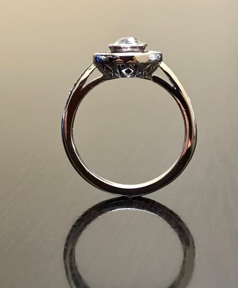 May include: A silver engagement ring with a round, clear center stone surrounded by a halo of smaller stones. The ring has a delicate band.