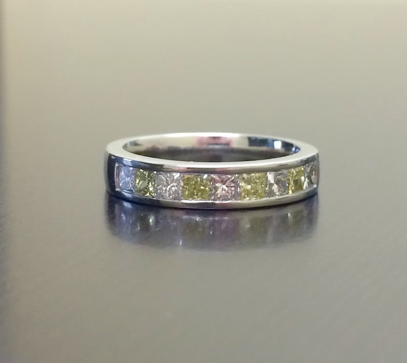 May include: A silver band ring with a row of small square-shaped diamonds. The diamonds are a mix of clear and yellow.