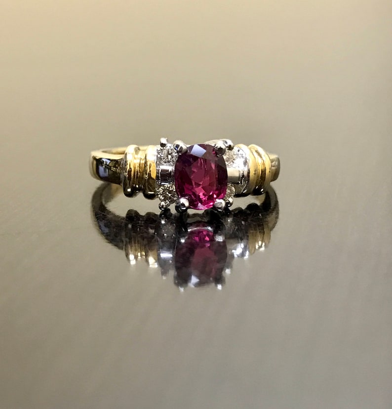 May include: A gold and silver ring with a large oval-shaped purple gemstone surrounded by smaller diamonds.