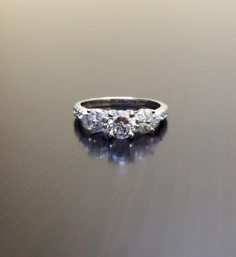 May include: A silver ring with three round diamonds. The centre diamond is larger than the two diamonds on either side.
