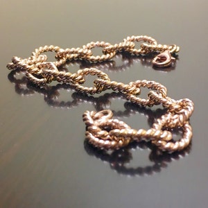 Puede incluir: Un brazalete de cadena de oro con un dise&ntilde;o de cuerda. La cadena est&aacute; hecha de eslabones ovalados.