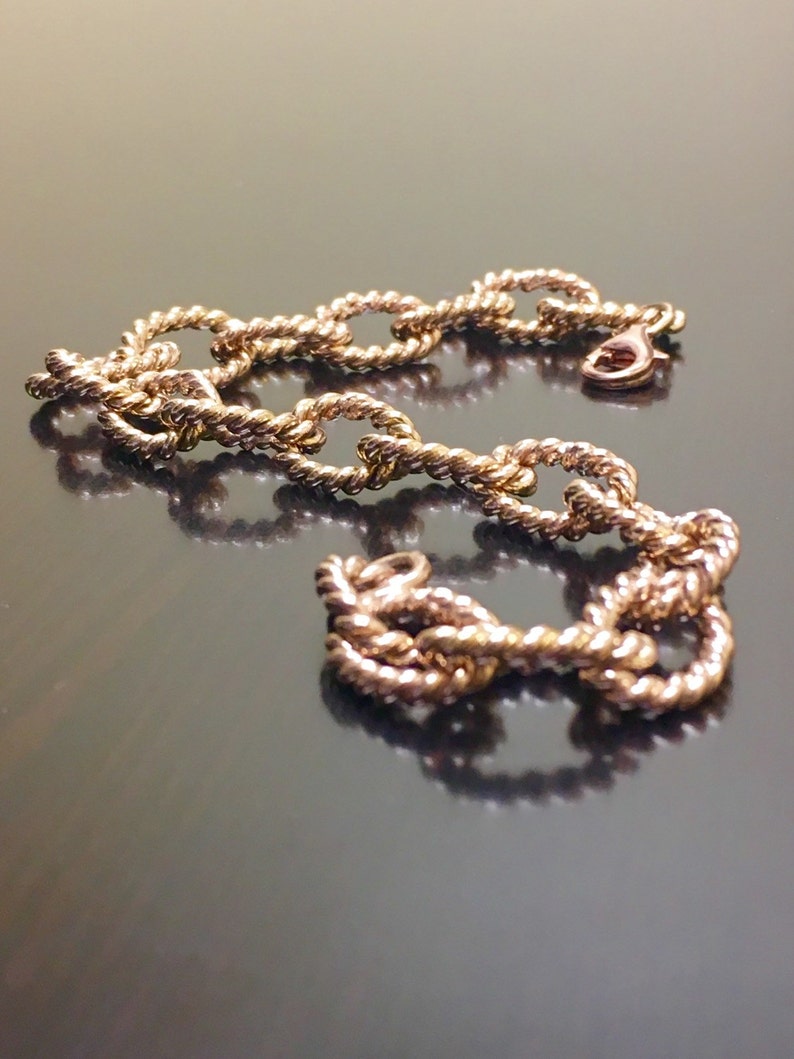 Puede incluir: Un brazalete de cadena de oro con un dise&ntilde;o de cuerda. La cadena est&aacute; hecha de eslabones ovalados.