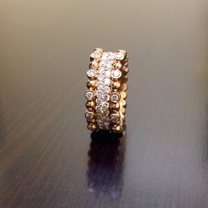 Pu&ograve; includere: Un anello a fascia d'oro con tre file di piccoli diamanti rotondi.