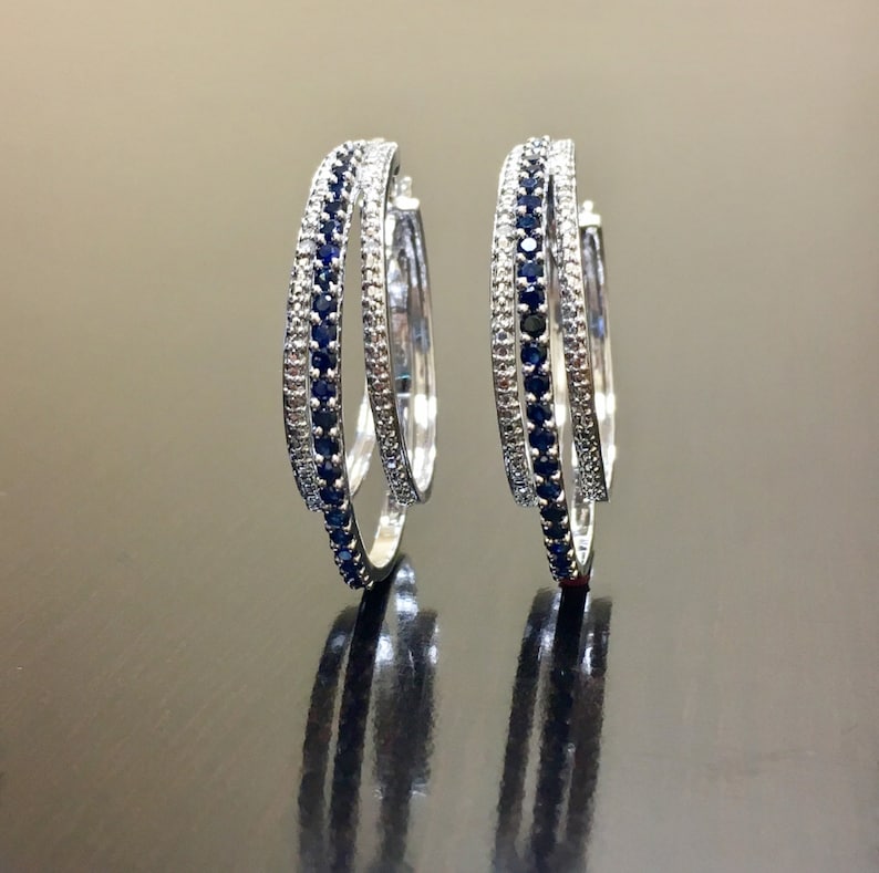 May include: A pair of silver hoop earrings with a double row of blue gemstones.