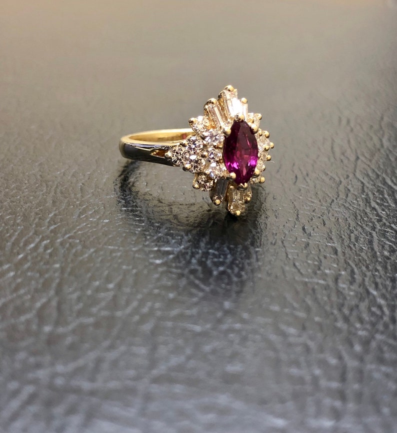Op de afbeelding: Een gouden ring met een grote peervormige robijn omringd door kleinere diamanten.