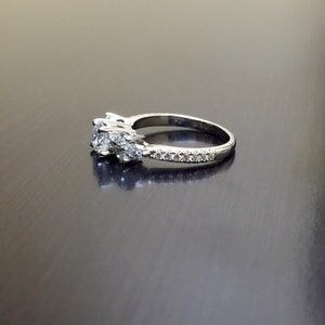 May include: A silver engagement ring with a large centre diamond and two smaller diamonds on either side. The band is set with smaller diamonds.
