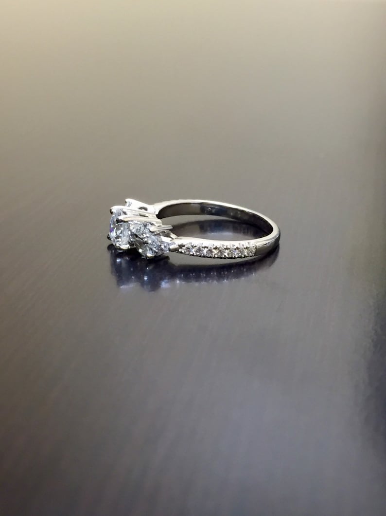 May include: A silver engagement ring with a large centre diamond and two smaller diamonds on either side. The band is set with smaller diamonds.