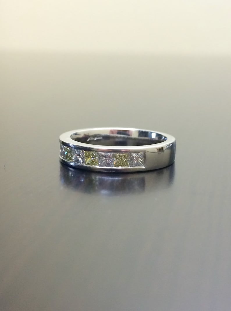 May include: A silver band ring with a row of clear and yellow square-shaped gemstones.